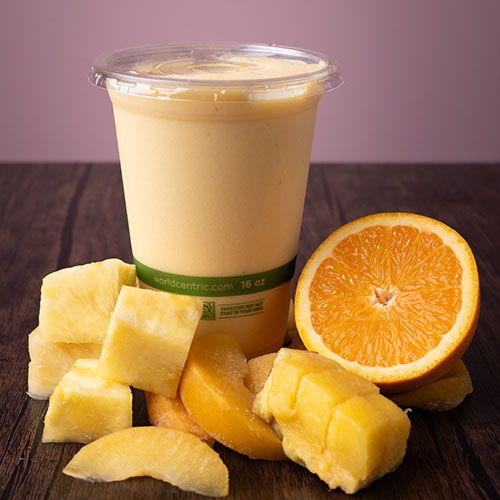 light orange colored smoothie next to fruit